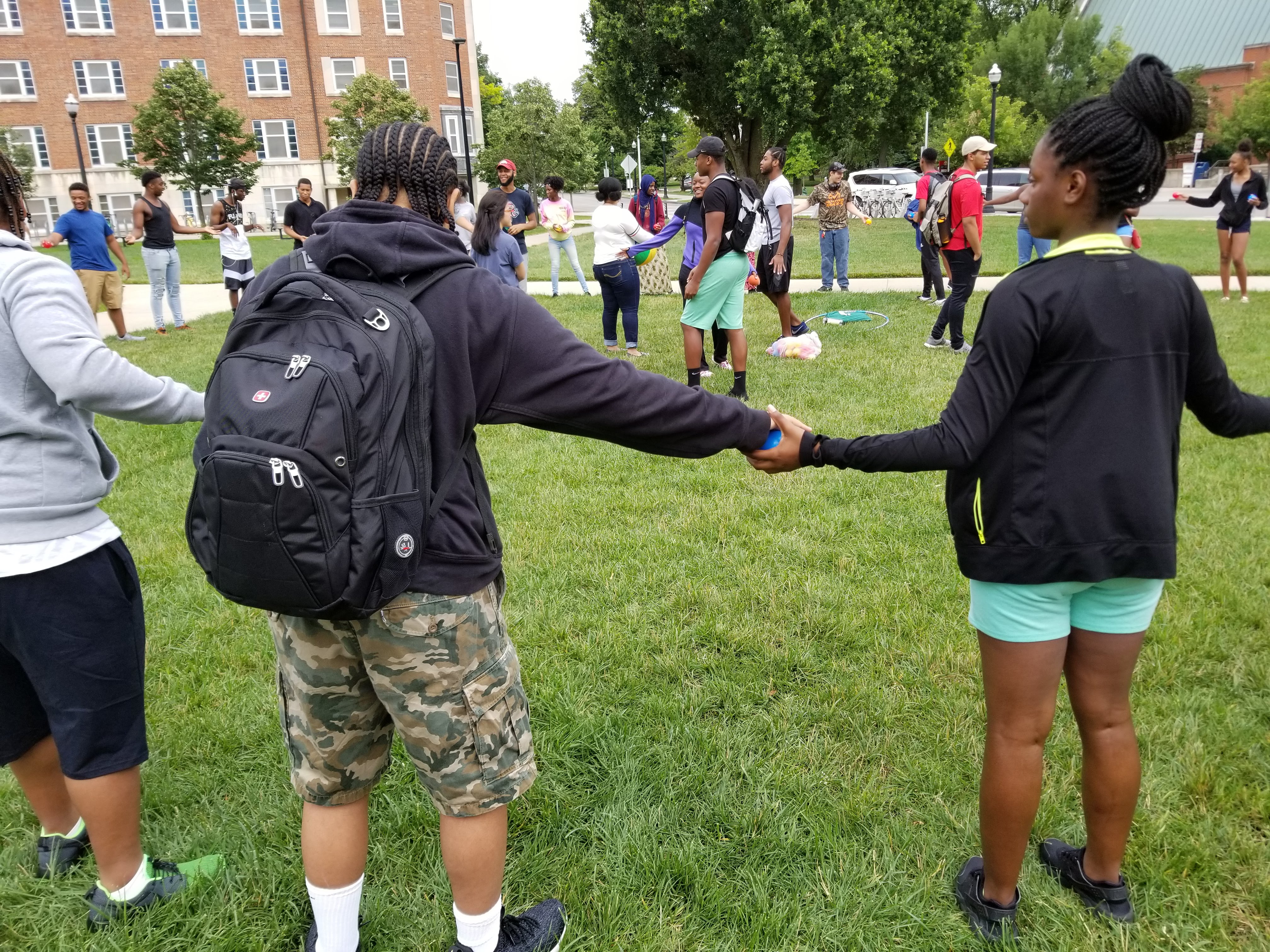 Group of UB scholar stand in a circle and hold hands