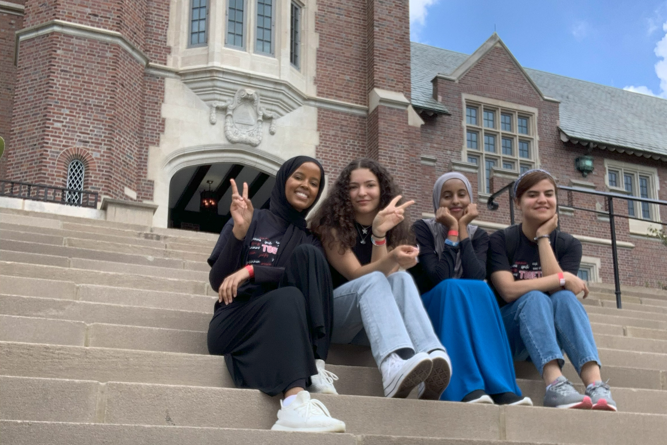 Four girls in black shirts sit on the steps of a building at Ohio State