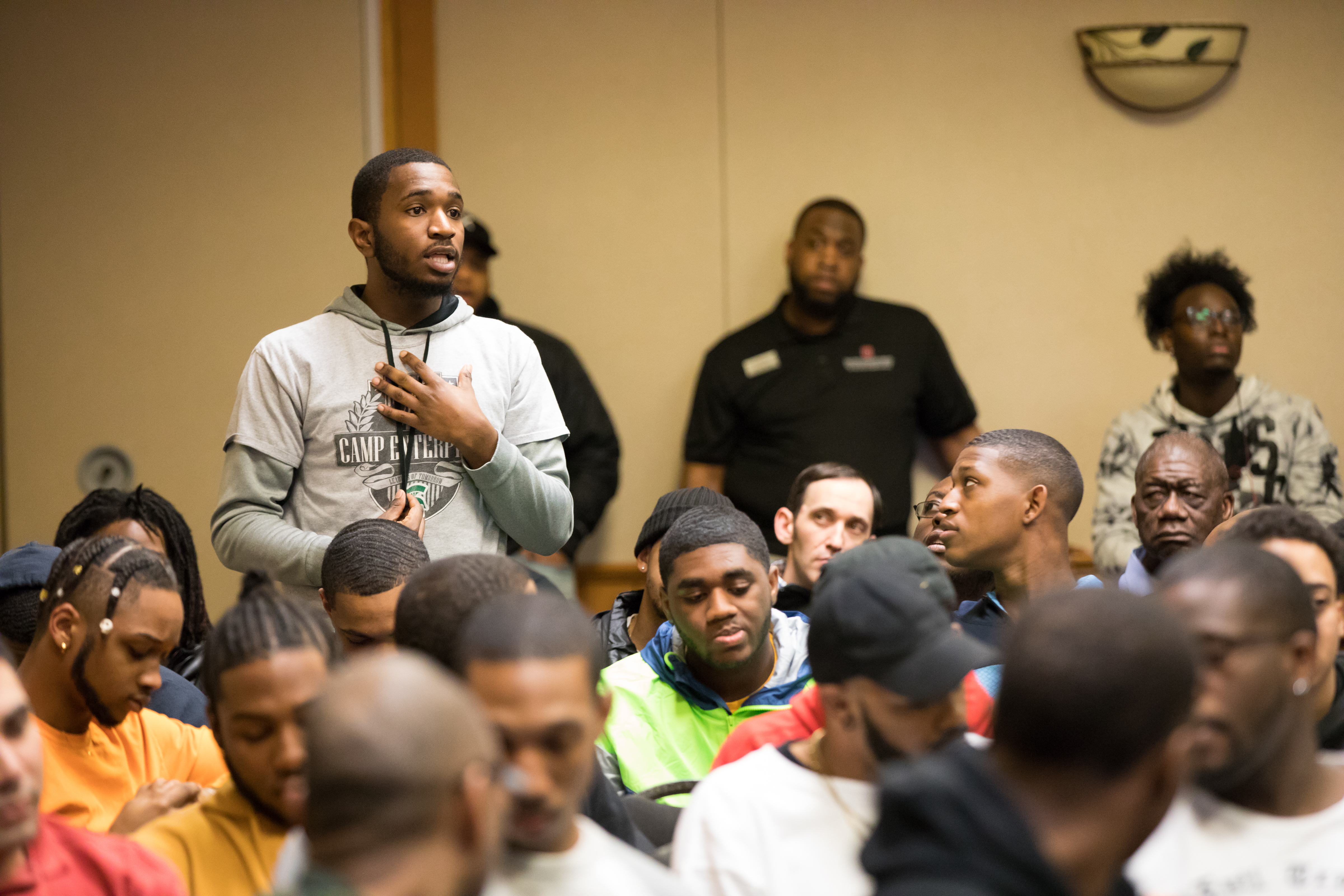 Man standing in seated group of people to ask a question