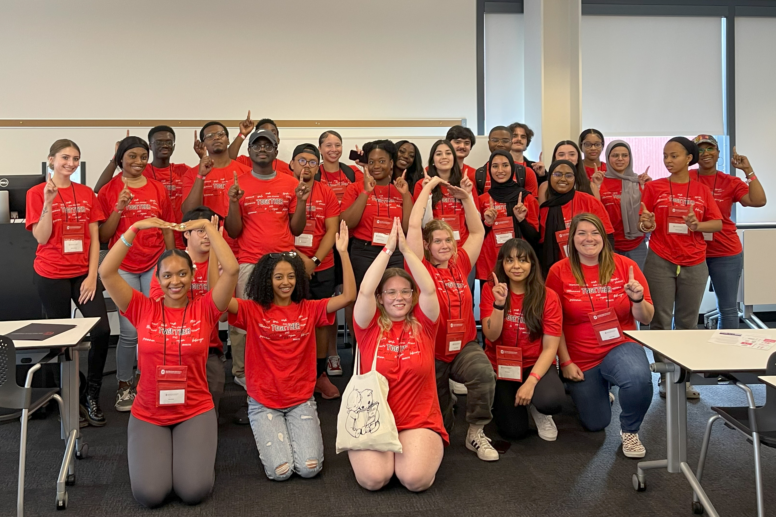 JLM Scholars in red matching t-shirts make an OH-IO with their arms