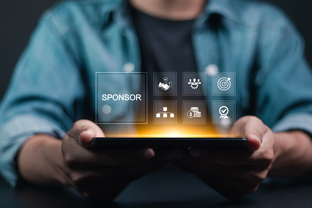 Man holding a glowing tablet with icons for sponsorships above it.