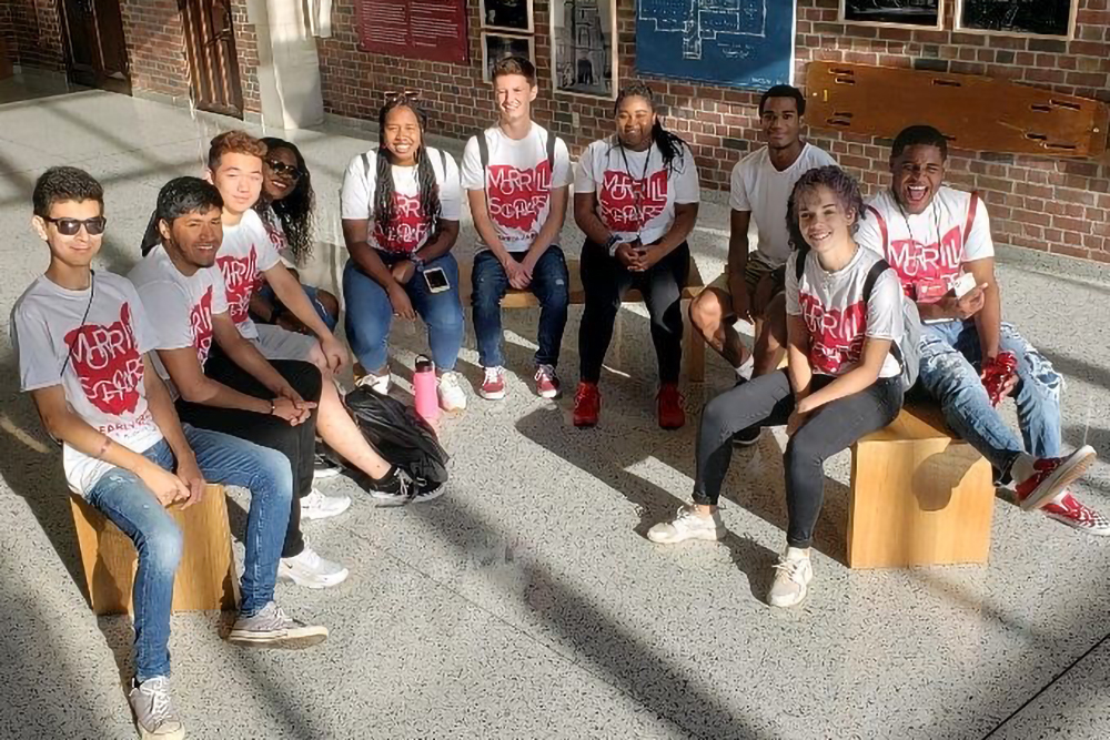 MSP students sitting inside a building on wooden benches in MSP t-shirts