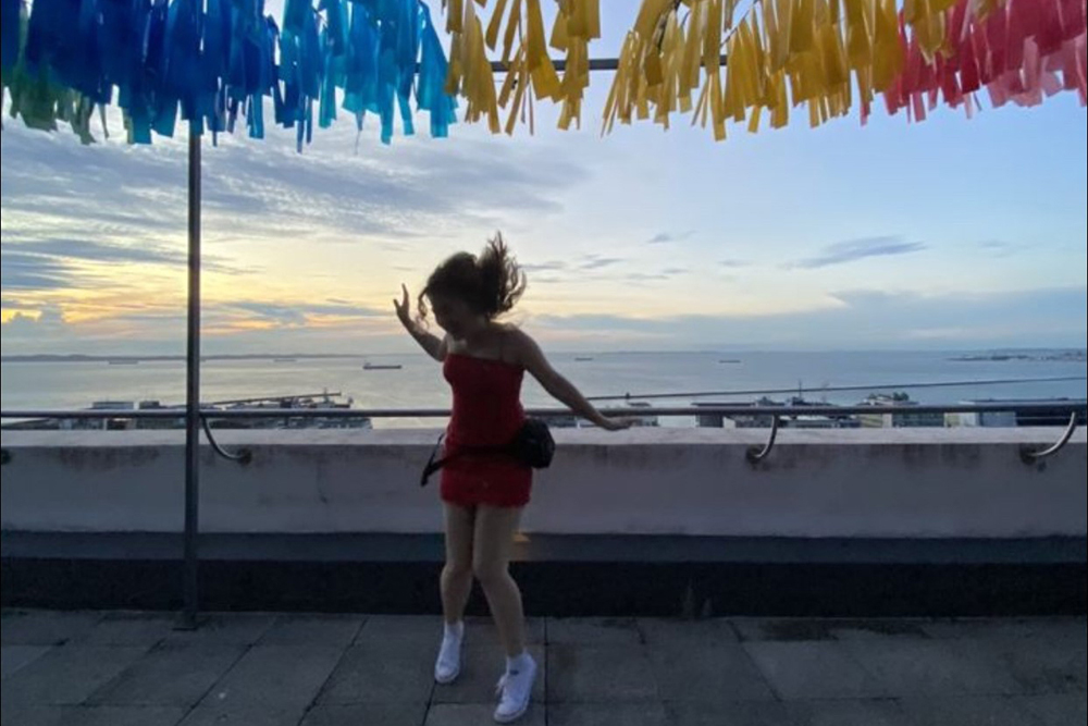 Young girl jumps in the air in front of a setting sun with colorful strips of paper hanging overhead