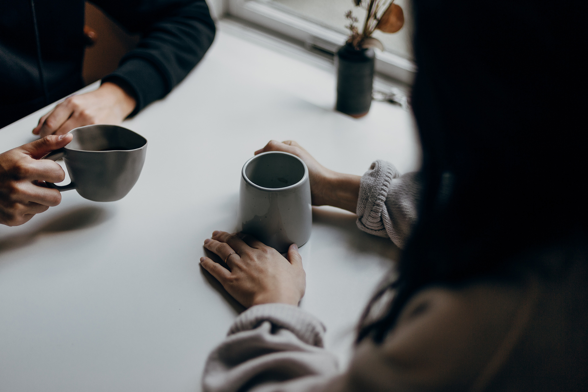 Hands of two people sitting at a table drinking water