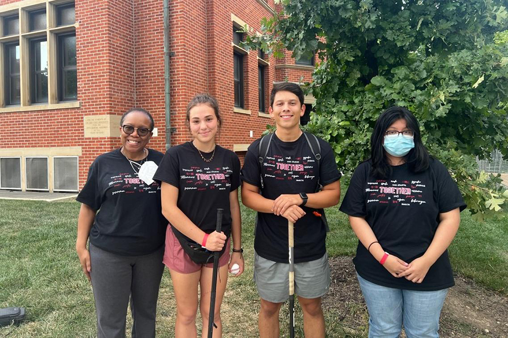 Four people wearing black shirts that say "together" stand in a row