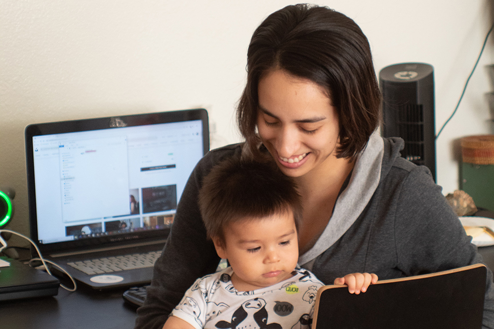 Mom holding baby with laptop open in the back