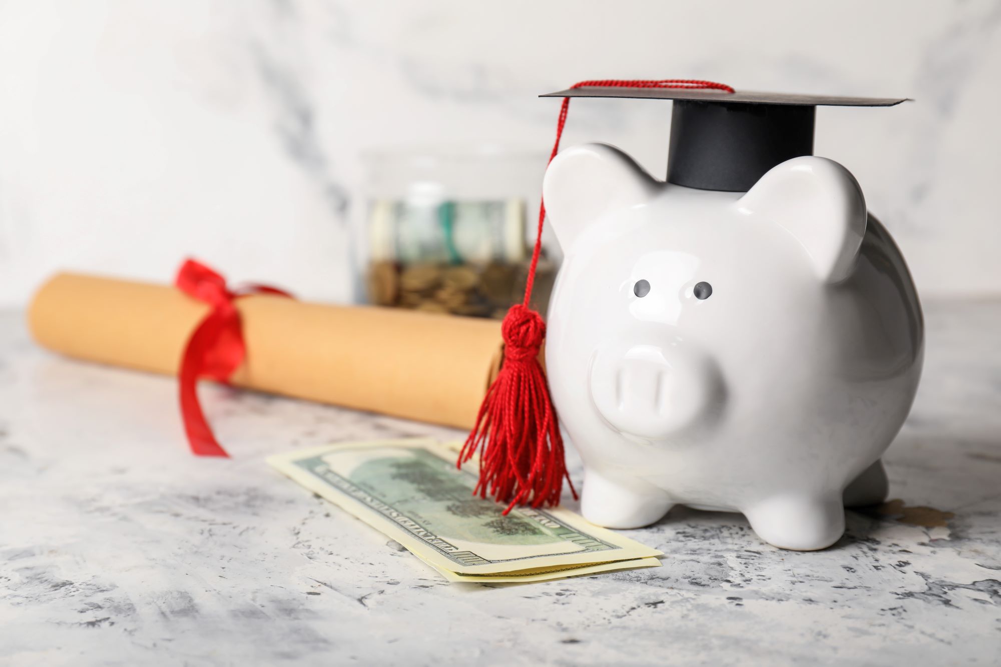 Piggy Bank with graduation cap in it and next to a diploma