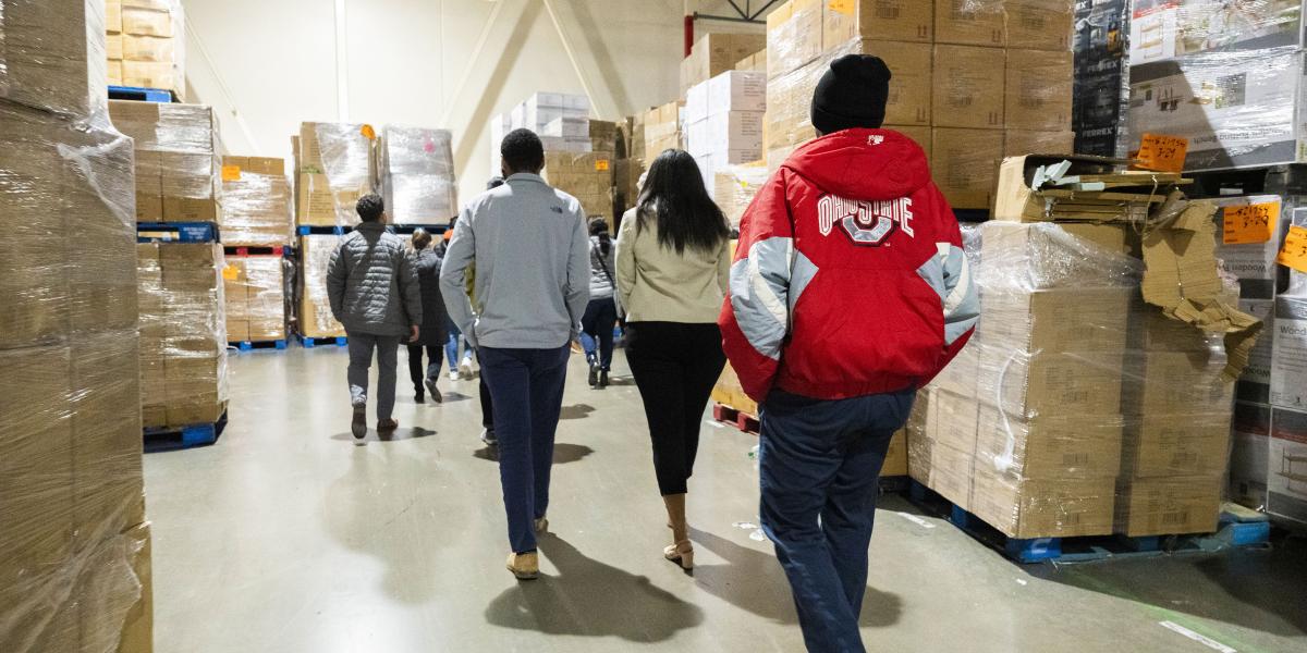 ODI Scholars walk through an Aldi's warehouse with boxes all around them