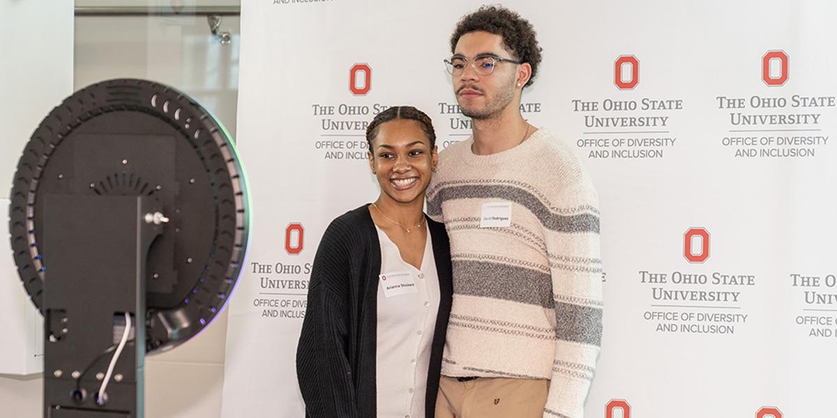 Two Black students stand in front of photo booth with ODI logos behind them