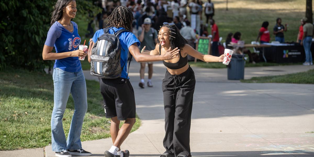 A woman and a man joyfully get ready to hug each other in greeting