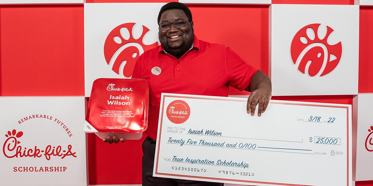 Isaiah Wilson, a Black man, holding his check for $25,000 scholarship