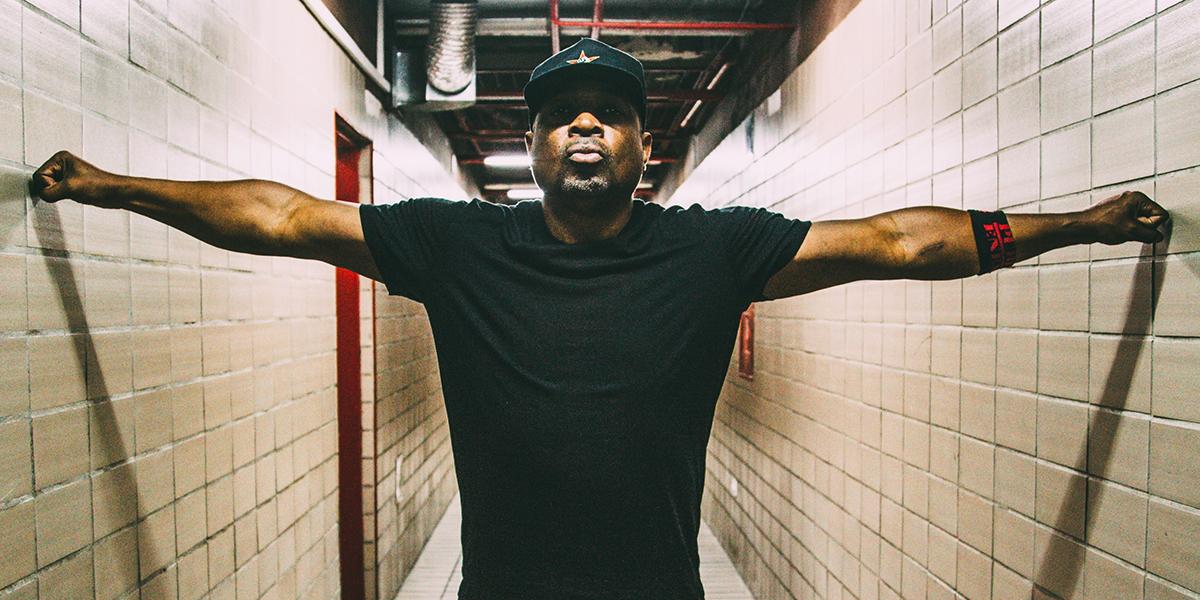 Chuck D in a hallway with his hands resting on each wall.