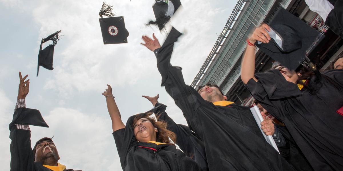 Ohio State grads throw their caps into the air at graduation in Ohio Stadium