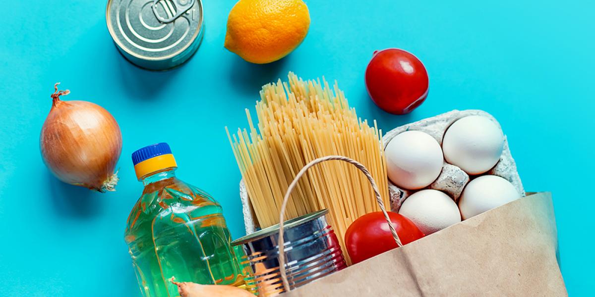 Bag of groceries with fruit, eggs, veggies, pasta, and a canned good