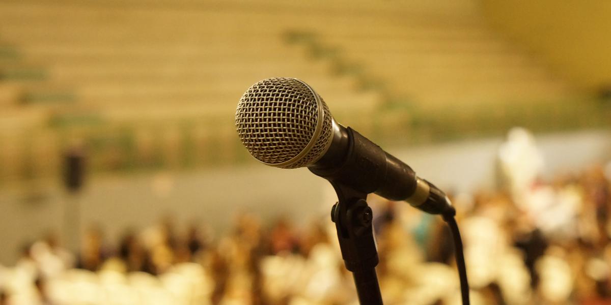 close-up of a mic with a blurred audience behind it