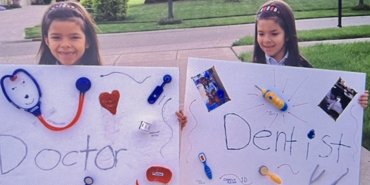 Twin sisters Cristina and Isabela Reina holding signs that say Doctor and Dentist.