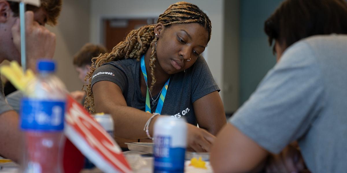 Latifat Sulaimon, a Black woman, works with coworkers at a table