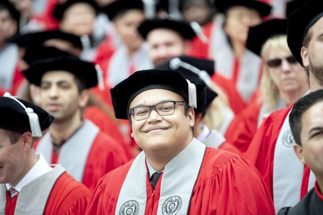 Ohio State PhD students in their regalia wait to be hooded