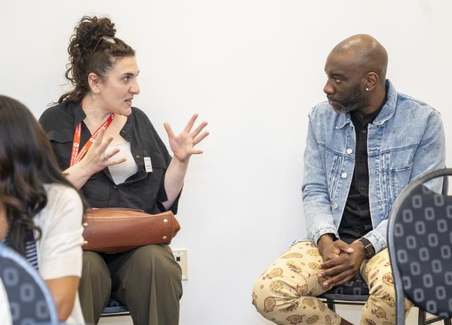 A woman gestures with her hand while talking to a man