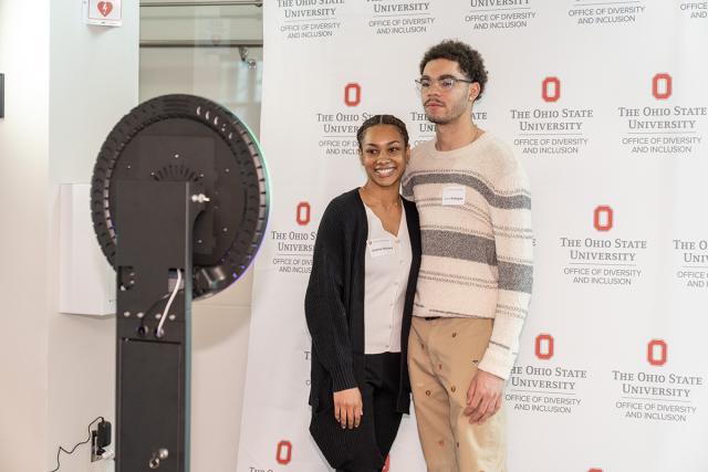 Two ODI Scholars stand in front of a ODI step and repeat