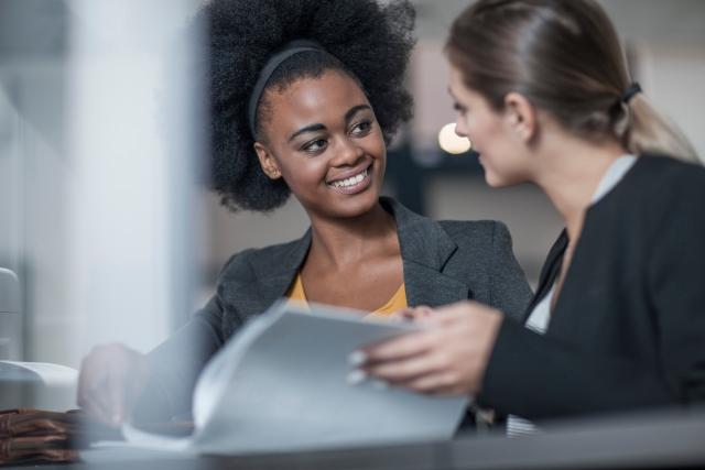 A women tutors a student who has an open book on the table in front of them