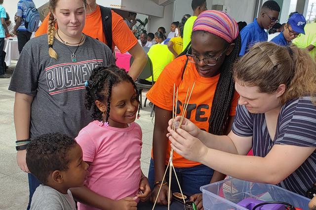 Group of students help a young Guyanan girl build a model