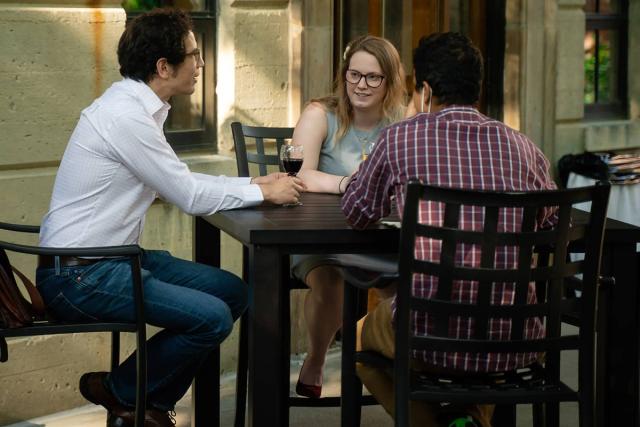 Three faculty members sit at an outdoor table talking