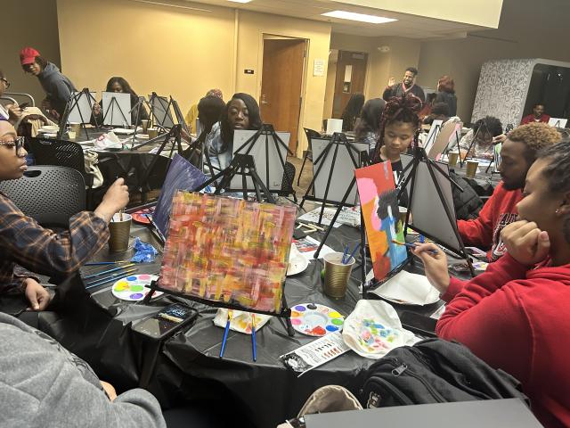 Poetry and Paint participants paint pictures around a table