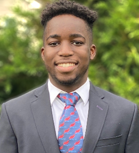 Jayden Simo in a grey suit jacket, white shirt with blue and red tie.