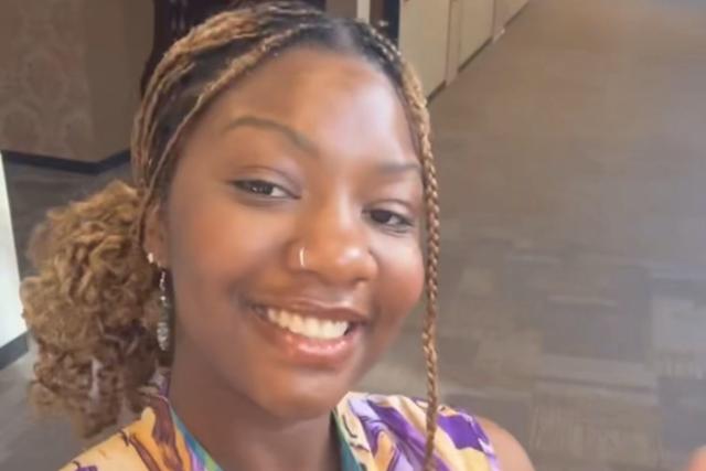 Latifat Sulaimon, a Black woman with braids, in a bright purple floral dress.