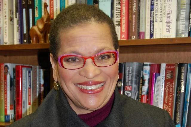 Dr. Julianne Malveaux, in bright pink glasses and an olive coat