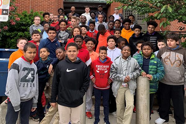 Middle School mentees stand on the steps of their school