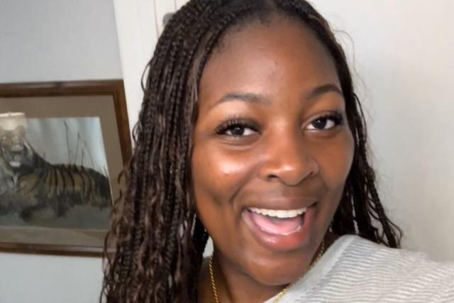 Paris Thompson, a Black woman, with long braids, wearing a light grey sweater