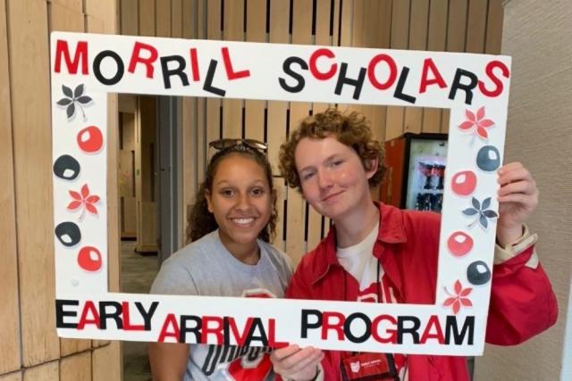 Two Morrill Scholars hold a frame around them that says Morrill Scholars Early Arrival Program