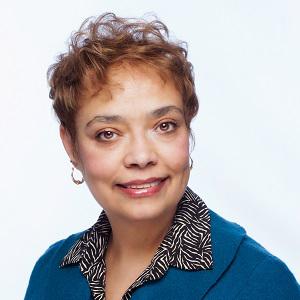 Congresswoman Charleta B. Tavares in a teal jacket and black and white shirt