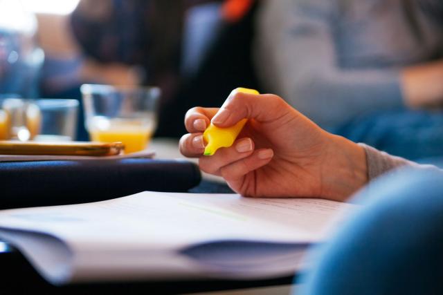 Person holding a highlighter pen while reading papers