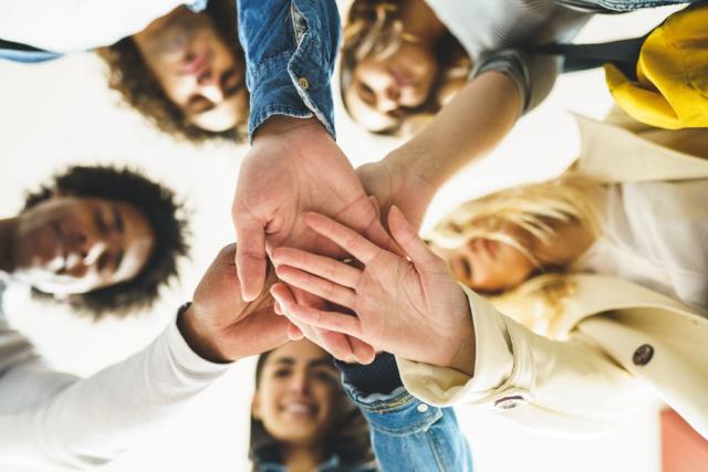 Shot of several people in a circle with their hands in the center