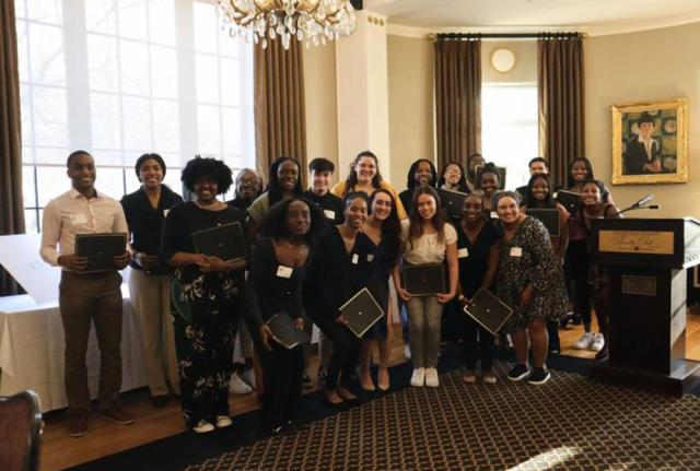 A group of students hold awards and pose for a photo