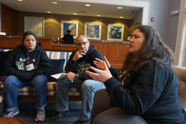 a man and two women grad students sit in chairs talking and gesturing