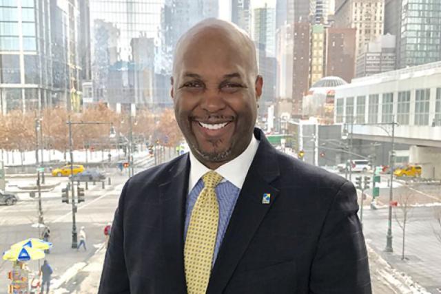 Cid Wilson in New York City in a black suit with yellow tie