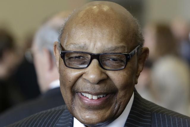 Louis Stokes in glasses and a pin-striped suit