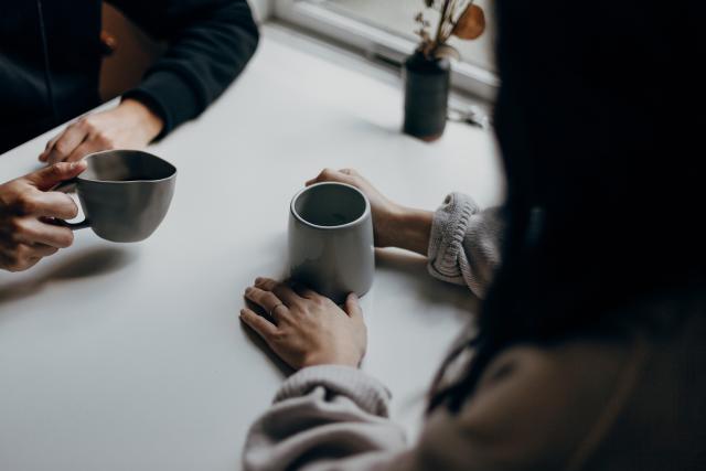 Two people with coffee cups sit at a table