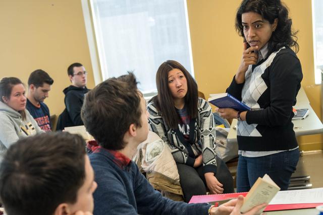 Professor teaches class holding a notebook