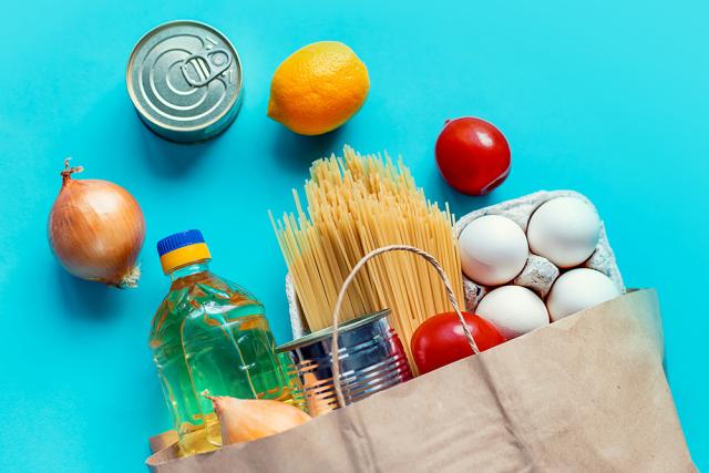 Bag of groceries with fruit, eggs, veggies, pasta, and a canned good