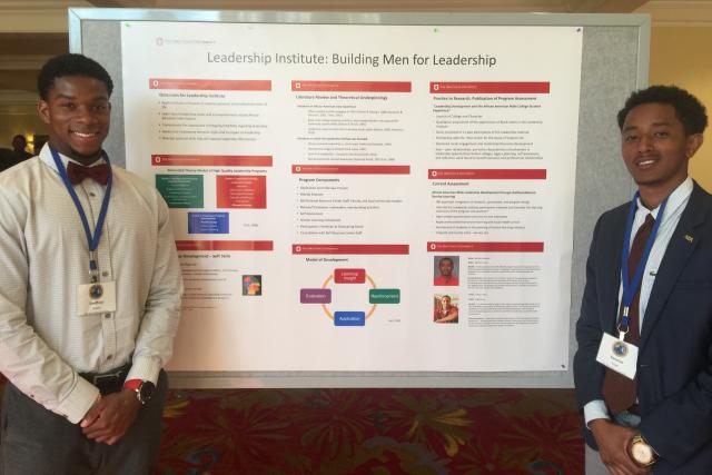 Two students stand in beside their research poster presentation