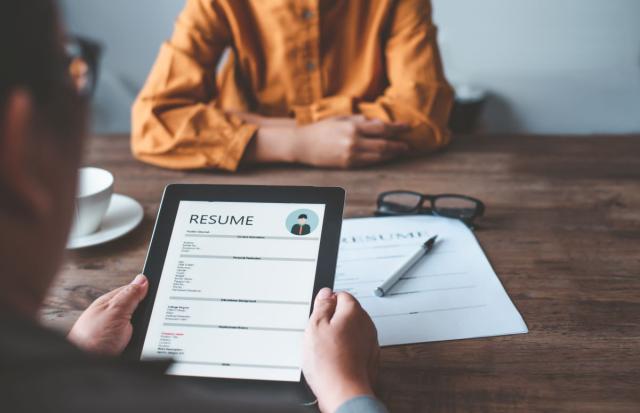 Woman sitting at a table while an interviewer looks at her resume