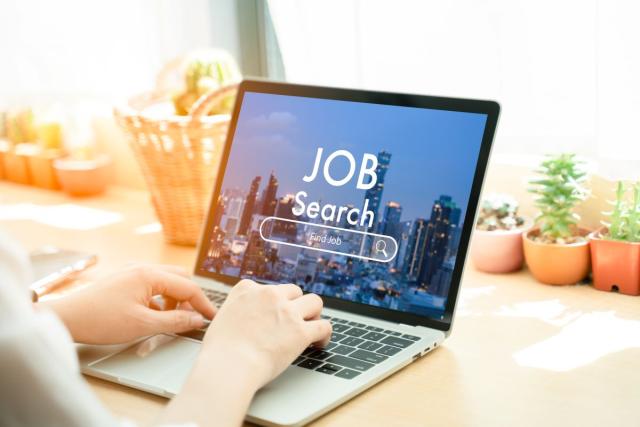 person typing at a computer that says Job Search on it