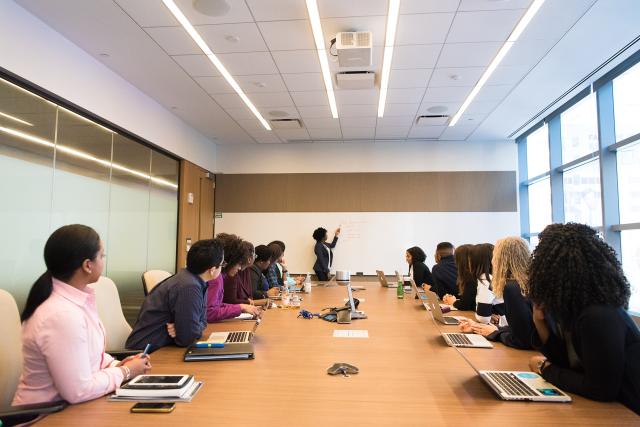 Large table with people around it looking at a presenter