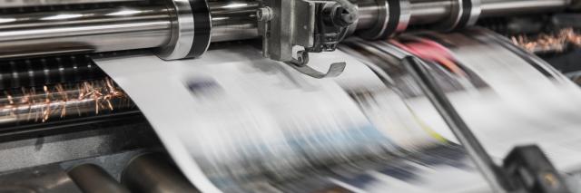 Newspaper traveling at high speed through a printing press