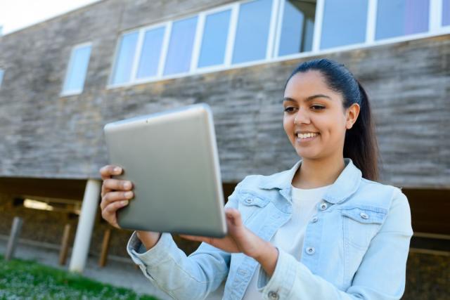 Student standing outside looking at her laptop